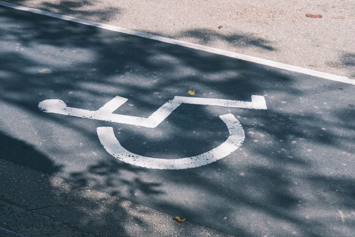 Accessible parking symbol painted on asphalt next to a white boundary line